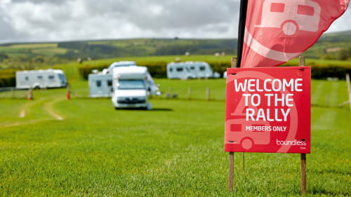 Boundless Camping and Caravanning group in a field with the flag at the front and caravans in the background